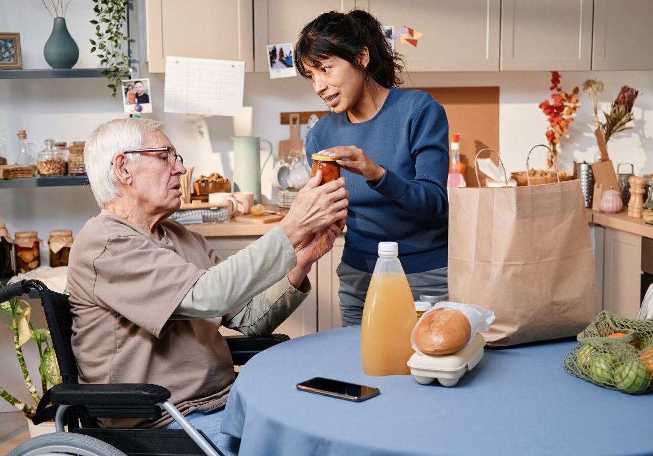 A woman is giving an elderly man some food.